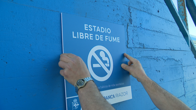 Un operario pon en Riazor o cartel que lembra a prohibición de fumar