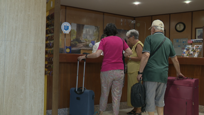 Turistas chegando á recepción dun hotel para pasar as vacacións de agosto