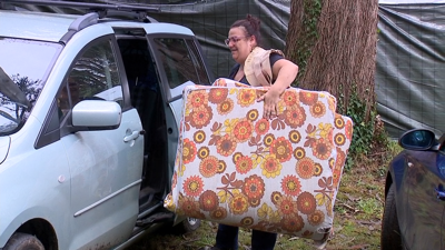 Unha muller descarga un colchón para levar á parcela onde pasan os días de festa