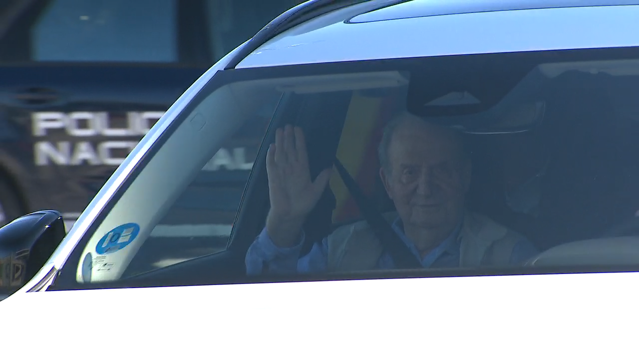 O rei Xoán Carlos saúda desde o coche de Pedro Campos tras aterrar en Peinador