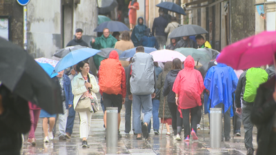 A xente protéxese da choiva en Santiago de Compostela