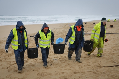 Operarios retiran bólas de plástico na praia de Corrubedo