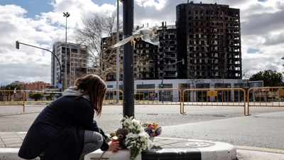 Unha muller deixa un ramo de flores ante o edificio incendiado. EFE/Ana Escobar
