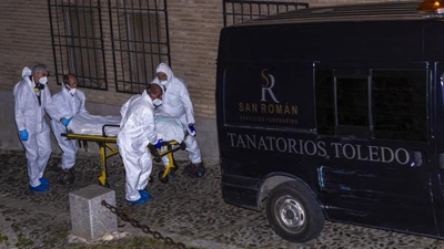 Membros dos servizos funerarios transportan un dos catro cadáveres atopados nunha vivenda de Toledo (EFE / Ángeles Visdómine)