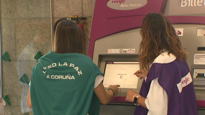 Traballadora de Renfe asistindo a unha usuaria nunha máquina de billetes